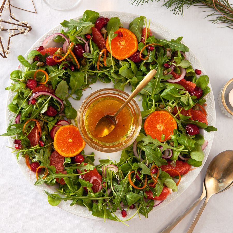 Kerstkrans van groene salade, grapefruit, granaatappel en sinaasappeldressing