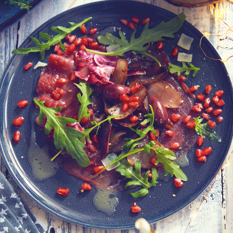 Carpaccio met gekonfijte sjalotjes in rode wijn, granaatappelpitjes en rucola